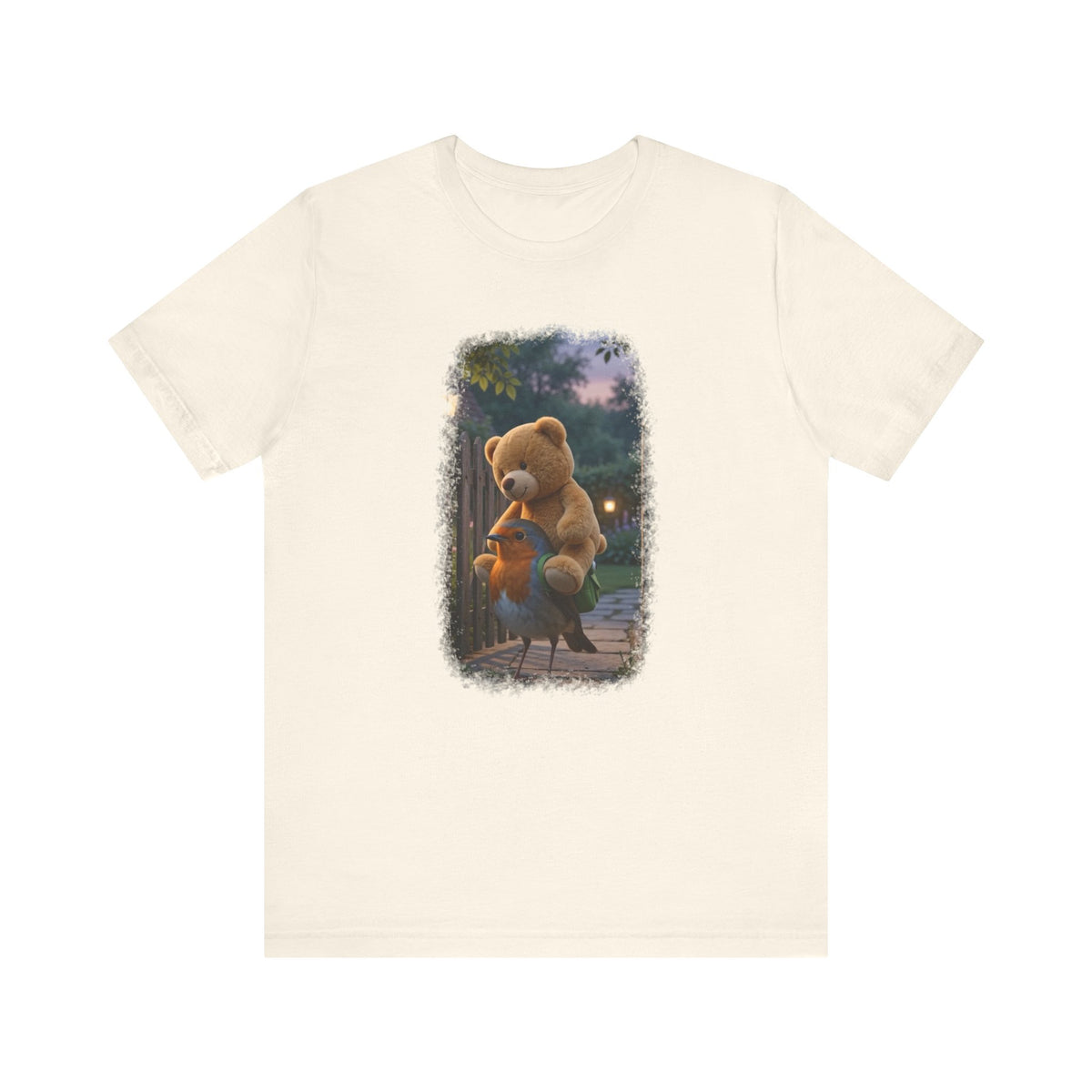Naturfarbenes T-Shirt aus Baumwolle. Auf der Brust ist eine witzige digitale Illustration aufgedruckt: Ein niedliches Rotkehlchen namens Rosi steht im Vorgarten und versucht, einen riesigen Kirmes-Teddybären in einen viel zu kleinen grünen Frosch-Rucksack zu quetschen.