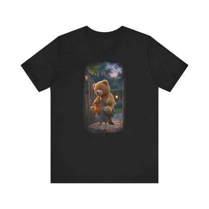Schwarzes T-Shirt aus Baumwolle. Auf der Brust ist eine witzige digitale Illustration aufgedruckt: Ein niedliches Rotkehlchen namens Rosi steht im Vorgarten und versucht, einen riesigen Kirmes-Teddybären in einen viel zu kleinen grünen Frosch-Rucksack zu quetschen.