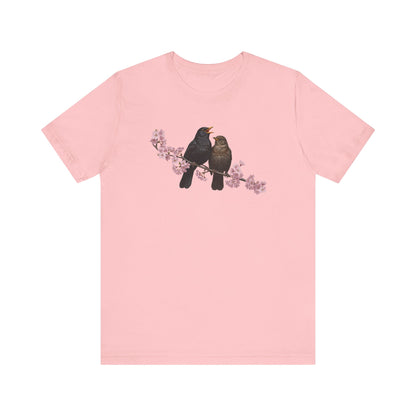 Pink t-shirt with two birds on a branch graphic on a white background