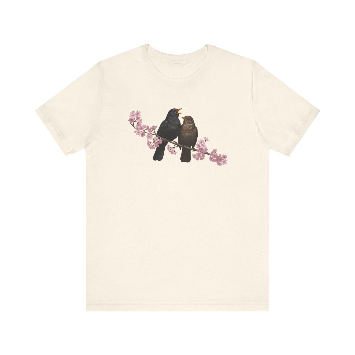 Beige t-shirt with a graphic of two birds on a branch with pink flowers on a white background