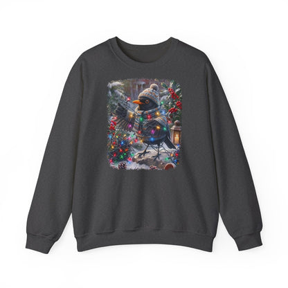Ein dunkelgraues Sweatshirt mit Rundhalsausschnitt und einem farbenfrohen Grafikdruck: eine Amsel in Winterkleidung und mit Mütze, die inmitten von Weihnachtsbäumen und Schnee eine Lichterkette hält.