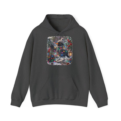 Ein dunkelgrauer Kapuzenpullover und einem farbenfrohen Grafikdruck: eine Amsel in Winterkleidung und mit Mütze, die inmitten von Weihnachtsbäumen und Schnee eine Lichterkette hält.