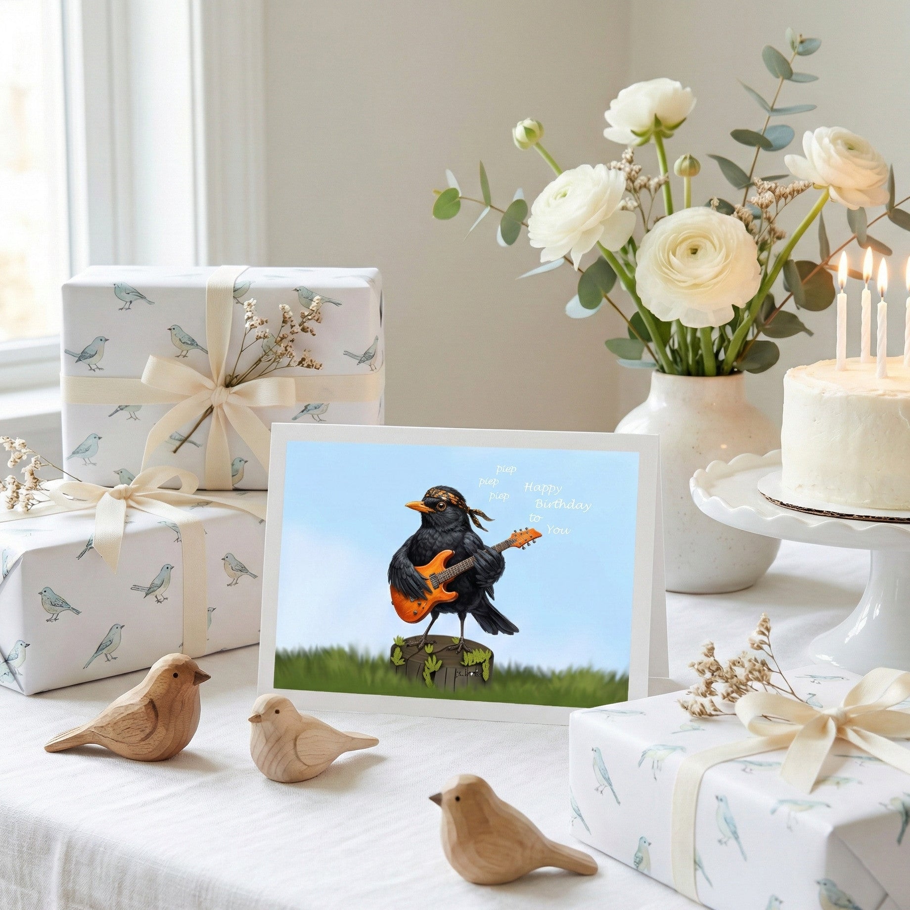 Gifts, a card with a bird playing guitar illustration, and decorative items on a table.
