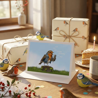 Greeting card with birds on a stand, surrounded by wrapped gifts and a cake.